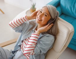 Mulher sorridente escutando música em um apartamento com conforto acústico